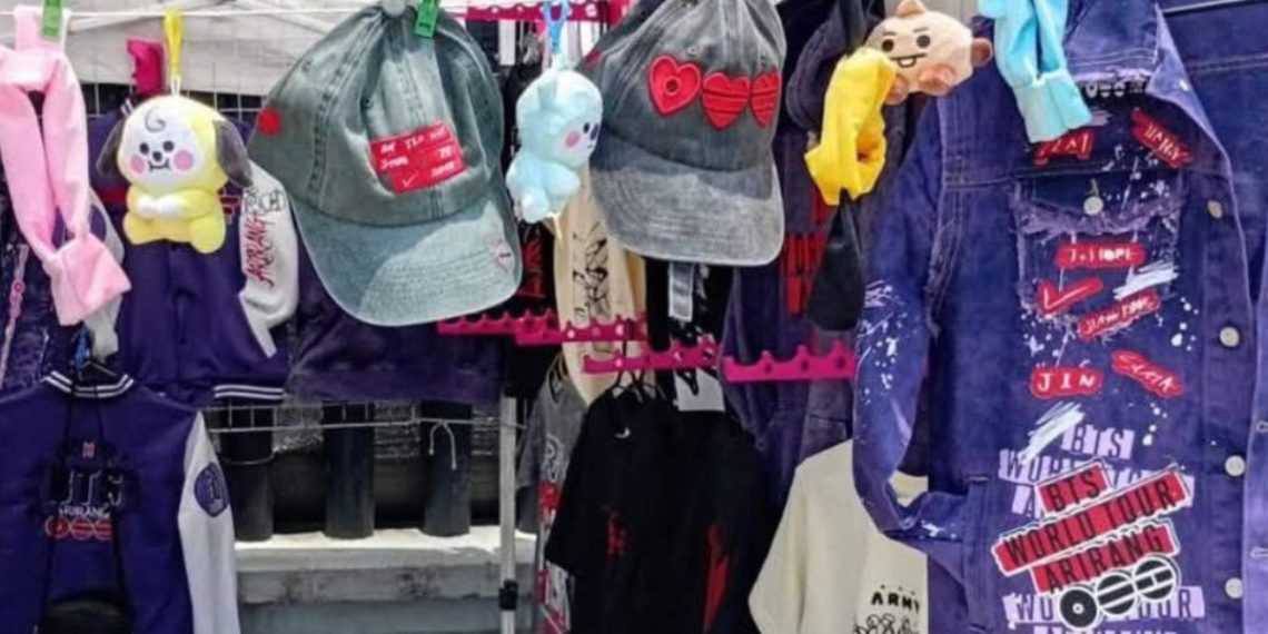 Clothes and accessories display: denim jackets, hats, and stuffed toys hanging on a market rack with pink clips and colorful decorations.