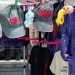 Clothes and accessories display: denim jackets, hats, and stuffed toys hanging on a market rack with pink clips and colorful decorations.