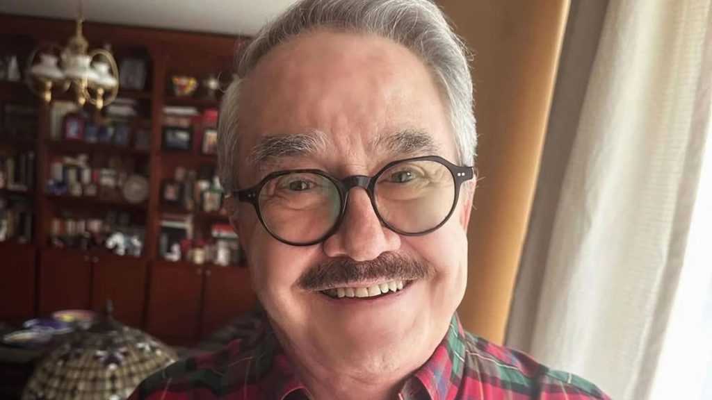 Pedro Sola sonriendo usando lentes de aumento y una camisa de cuadros